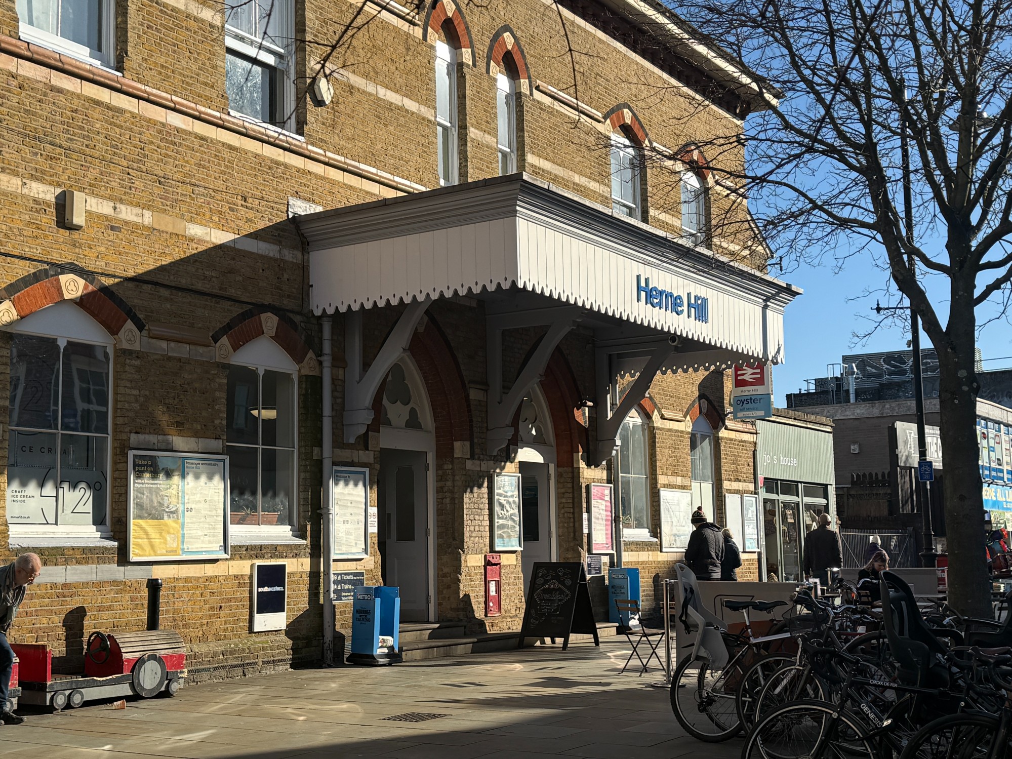 Side view of Herne Hill train station. Bikes parked up outside of the entrance.