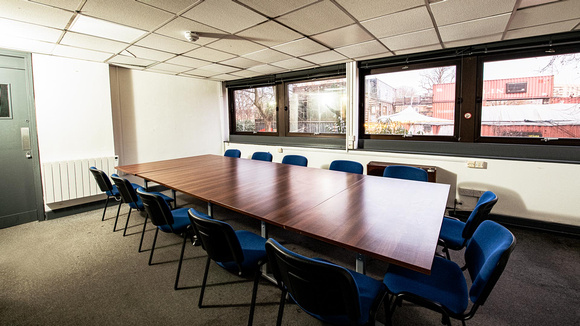 Office space within the Brixton Recreation Centre. A table with 12 blue chairs placed around it