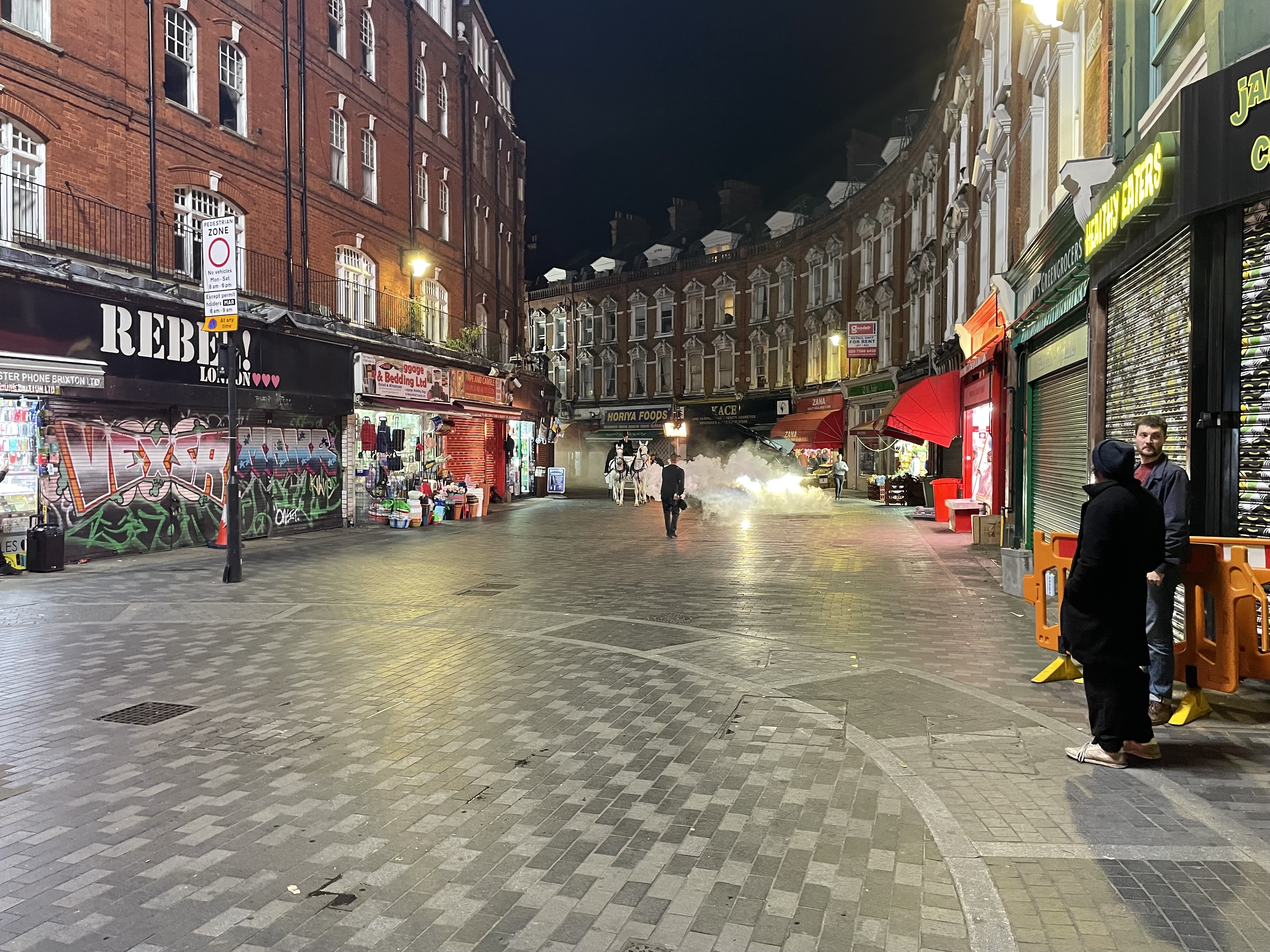 Pan shot of Electric Avenue. Row of shops curves round the bend of the street.