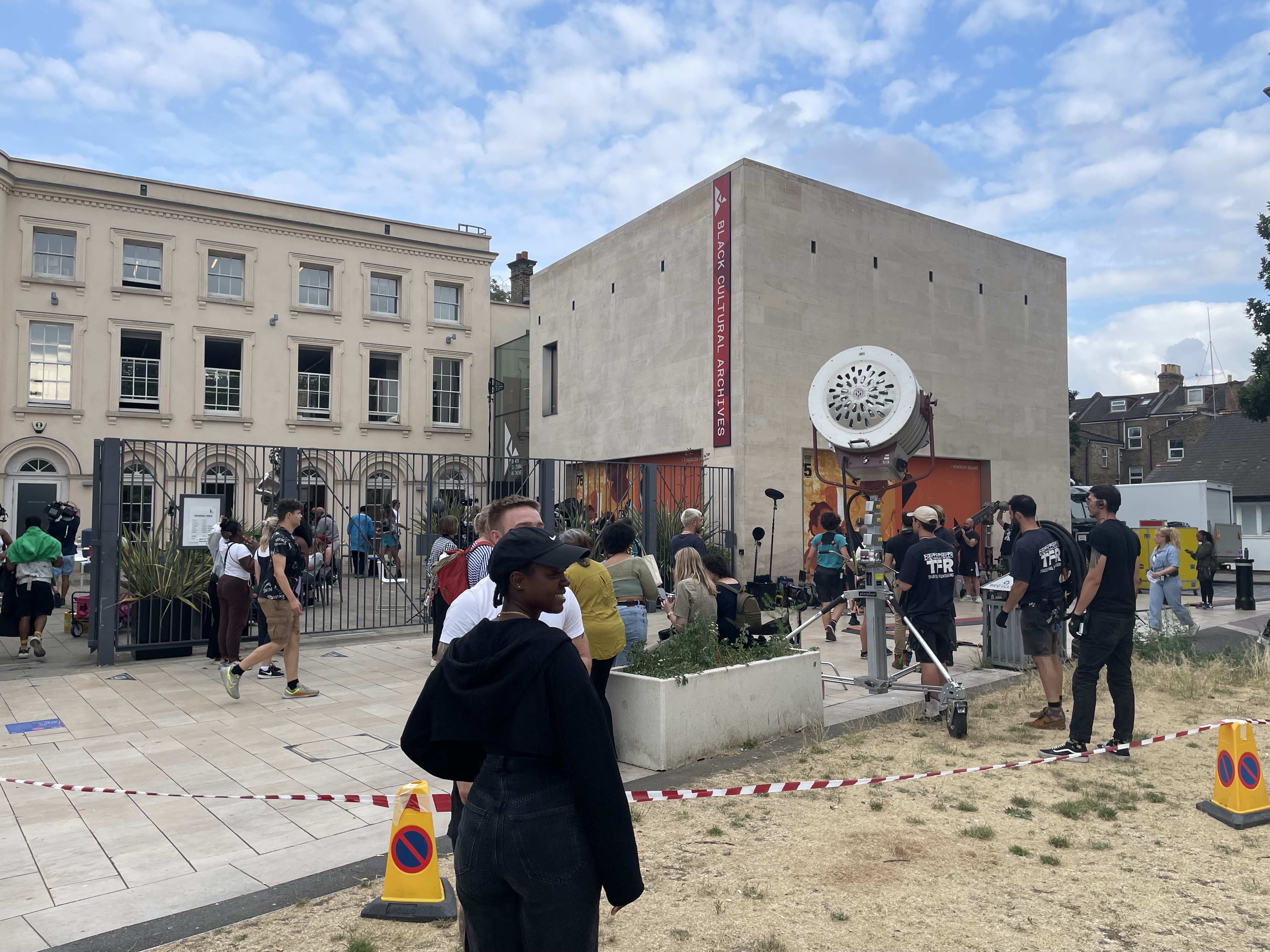 Crowd of cast and crew setting up for a shoot outside the Black Cultural Archives on Windrush Square in Brixton