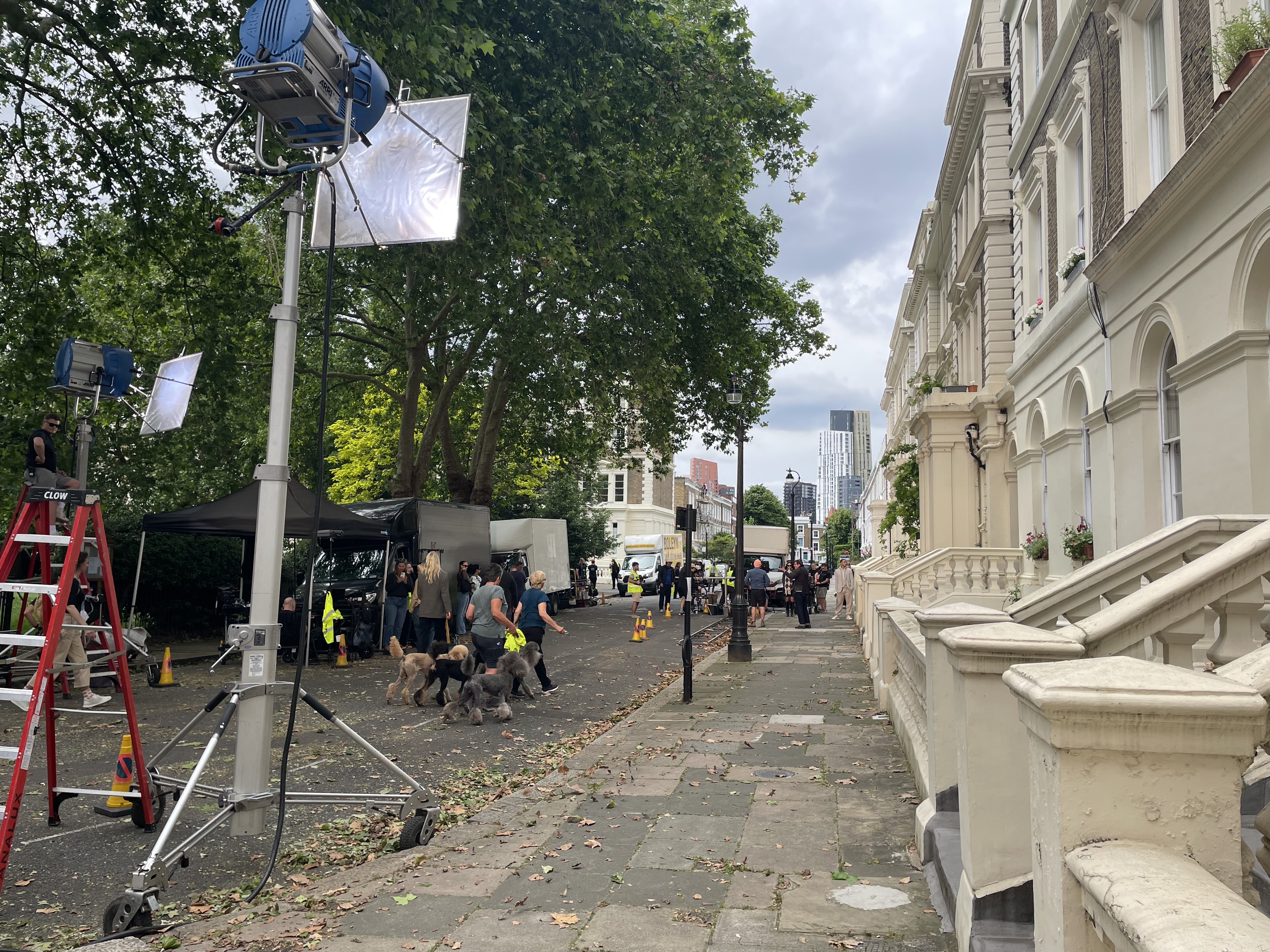 Cast and crew on a set for a Mark's and Spencer shoot on Albert Square. Staff walking 4 dogs onto set. 