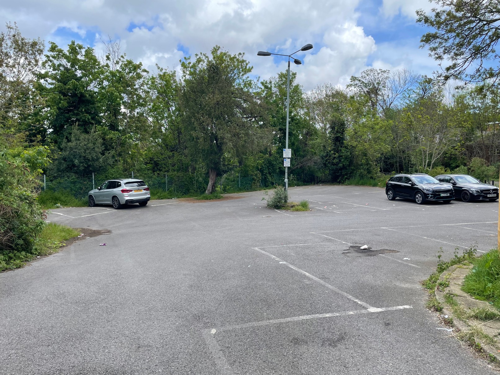 Empty parking lot with a few cars at Leigham Court Road, surrounded by trees and greenery.